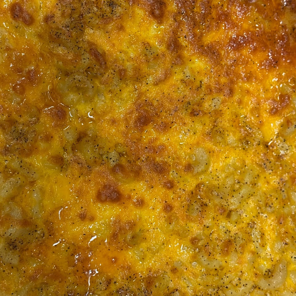 Close-up of baked macaroni and cheese with melted golden cheese and black pepper.