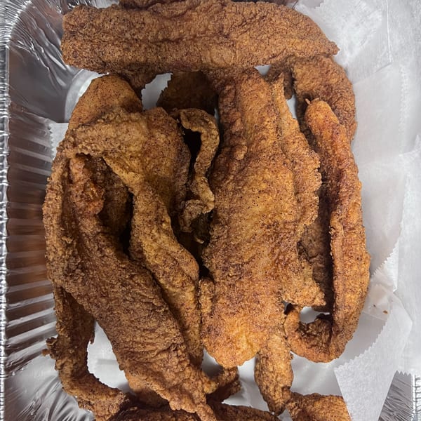 Crispy, golden-brown fried catfish fillets from C & E Southern Bites, served in a foil container.