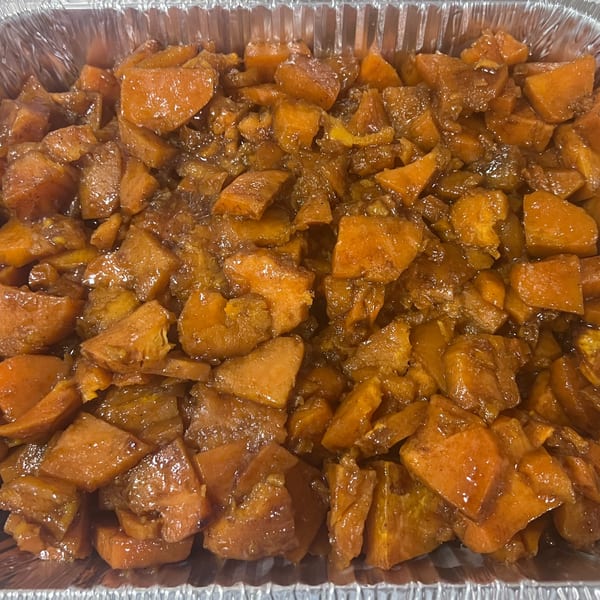 Close-up of candied yams, a Southern side dish, in a foil pan.