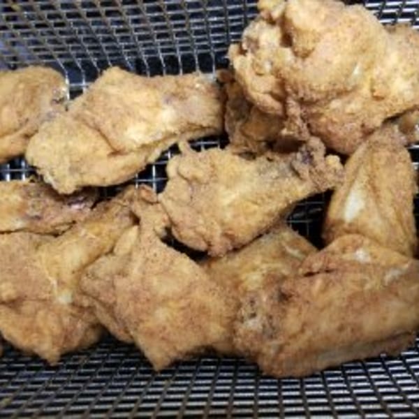 Crispy, golden-brown fried chicken pieces resting on a metal cooling rack.