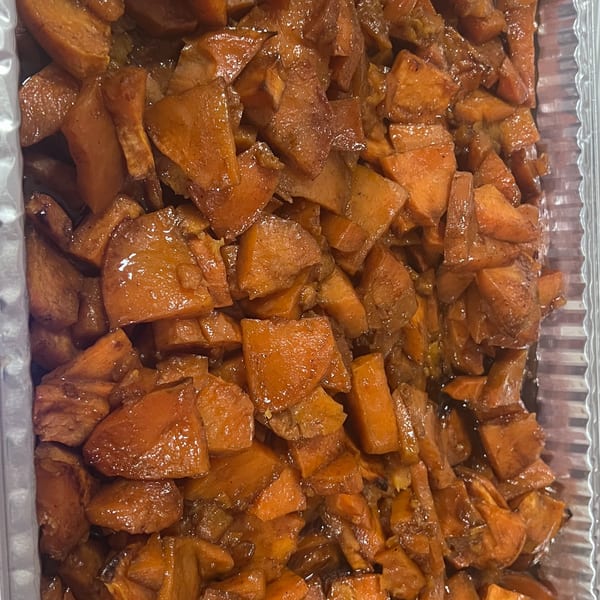 Close-up of candied yams, a Southern side dish, in a foil container.