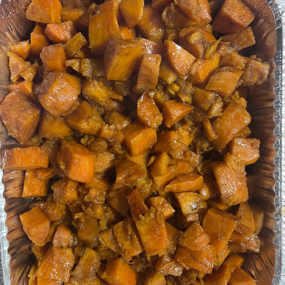 Close-up of candied yams in a foil pan, a sweet southern side dish from C & E Southern Bites.